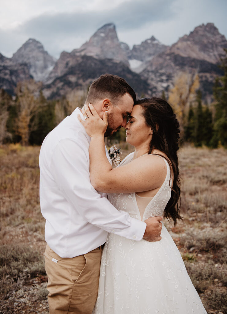 Jackson Wy photographer captures bride and groom embracing and touching foreheads in Grand Teton National Park