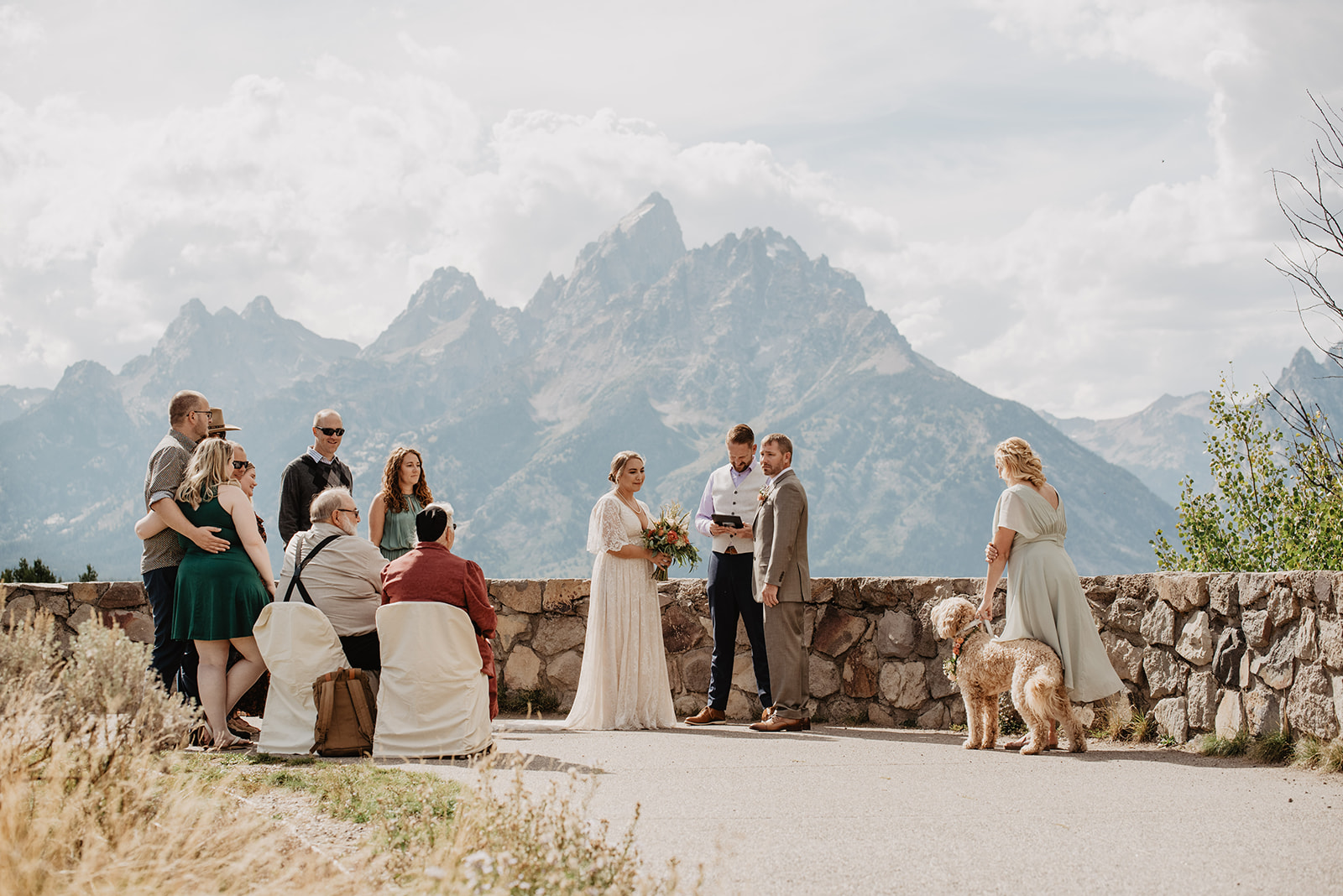 bride and groom getting married in the Tetons with a small group of guests surrounding them on the outlook captured by Jackson Hole photographer