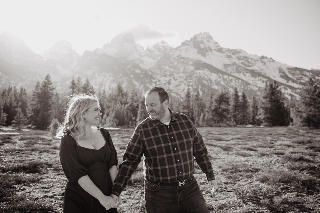 Jackson Wy photographer captures black and white portrait of man and woman holding hands and walking through Grand Teton National Park