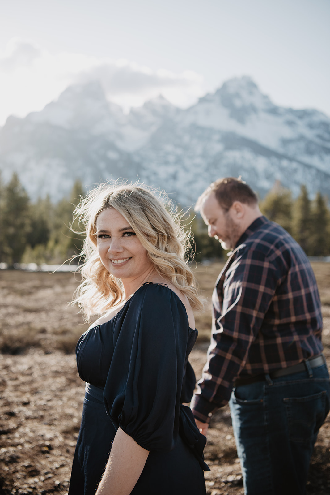 Jackson Wy photographer captures woman looking back while husband leads her into park during Jackson Hole Honeymoon