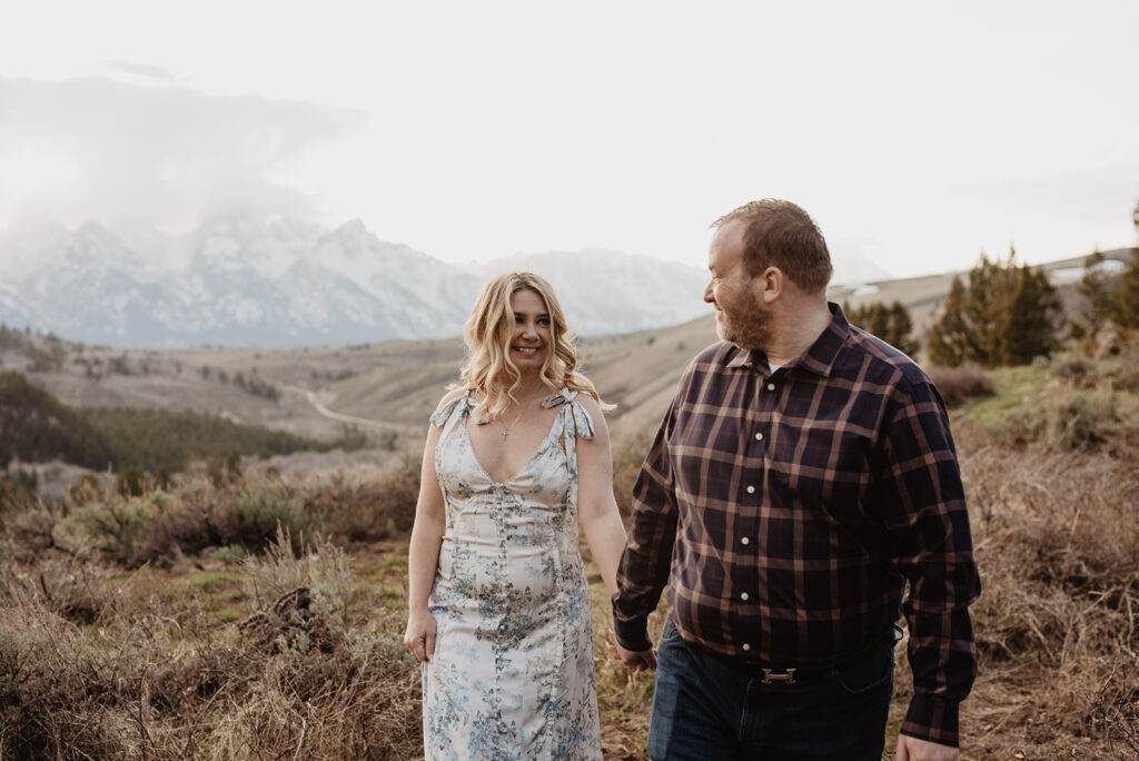 Jackson Wy photographer captures couple holding hands and looking at one another while walking through park