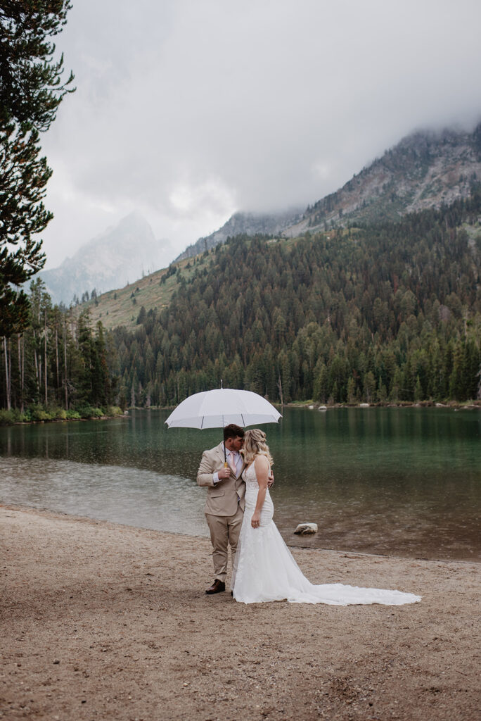 Jackson Hole Wedding Photographer captures bride and groom standing under umbrella