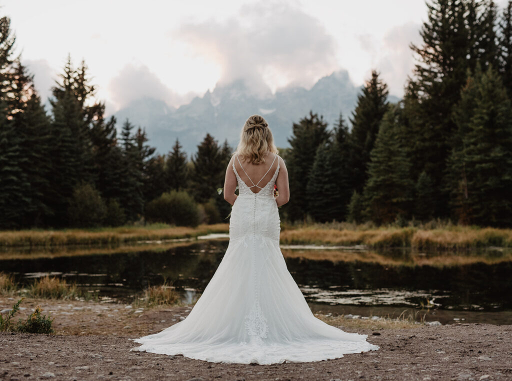 Jackson Hole Wedding Photographer captures bride looking over mountains with elegant wedding dress on