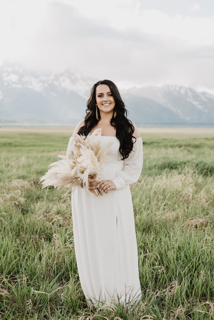 Wyoming Elopement Photographer captures bride wearing long sleeve wedding gown with boho bridal bouquet