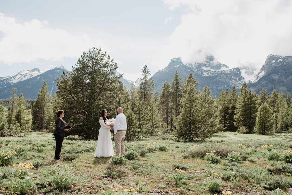 Wyoming Elopement Photographer captures couple walking through forest during engagement photos