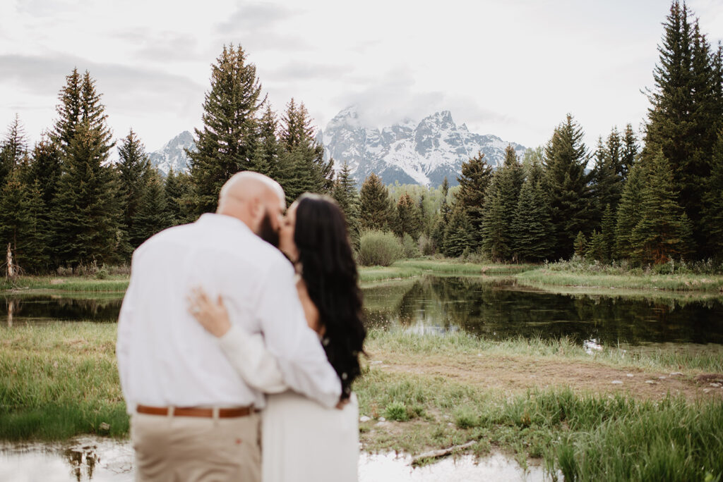 Wyoming Elopement Photographer captures bride and groom kissing, looking at mountains