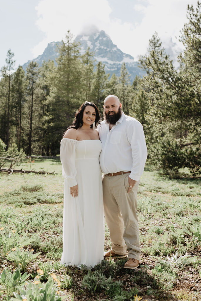 Jackson Hole photographer captures bride and groom portrait in the Tetons with couple embracing and smiling 