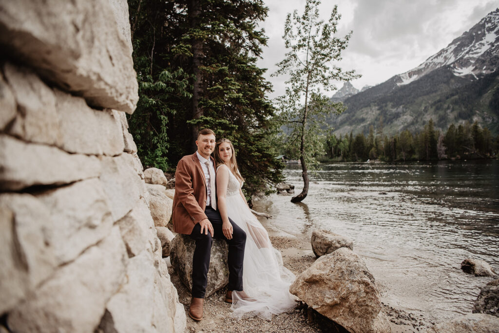Grand Teton Wedding Photographer captures bride and groom sitting on boulders during bridal portraits