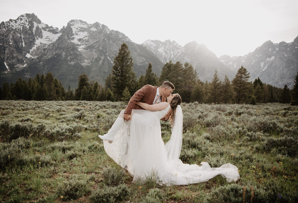 Grand Teton Wedding Photographer captures groom dip kissing bride in front of Tetons