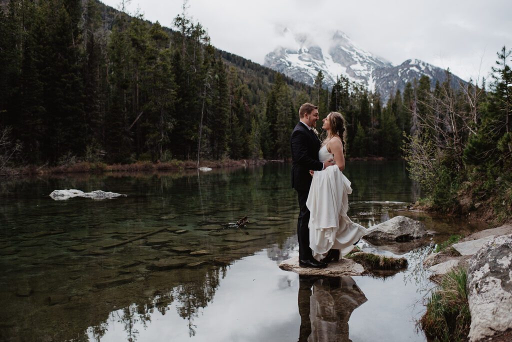 Jackson Hole Elopement Photographer captures bride and groom standing on rock in water