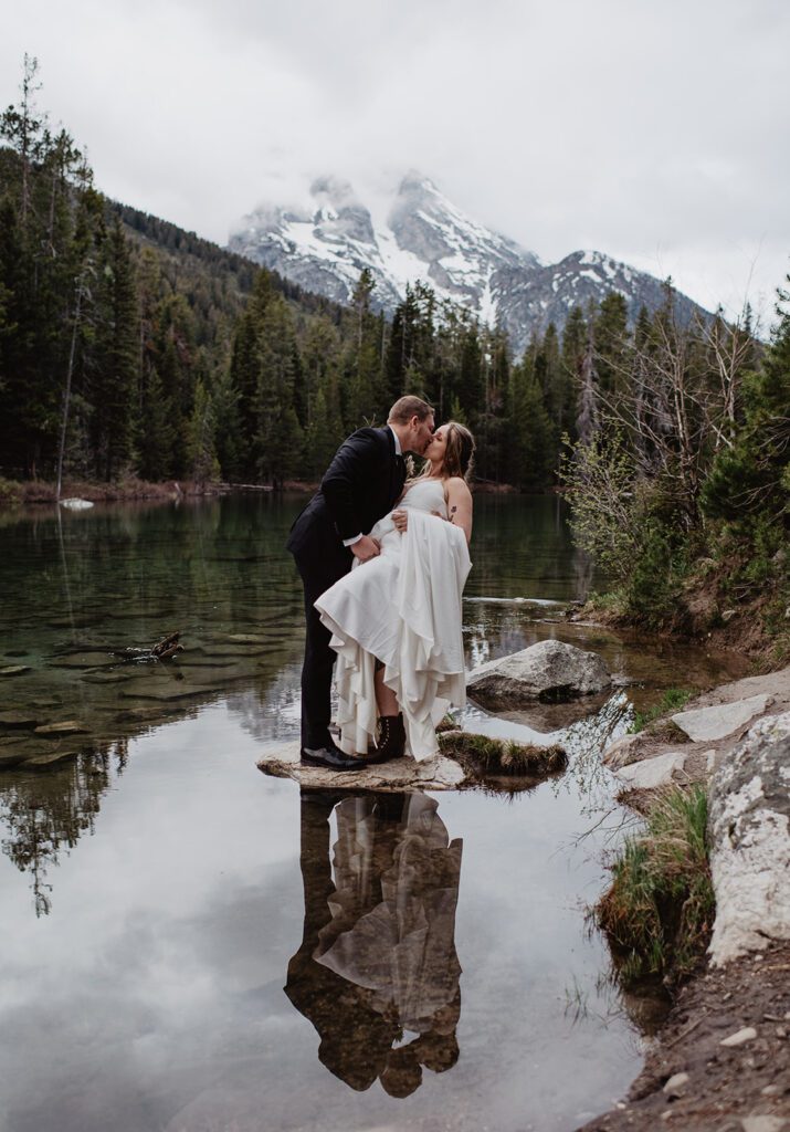 Jackson Hole Elopement Photographer captures bride and groom dip kiss on rock