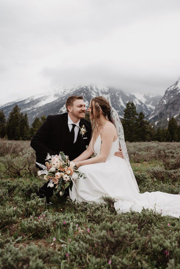 Jackson Hole Elopement Photographer captures bride and groom sitting in grass