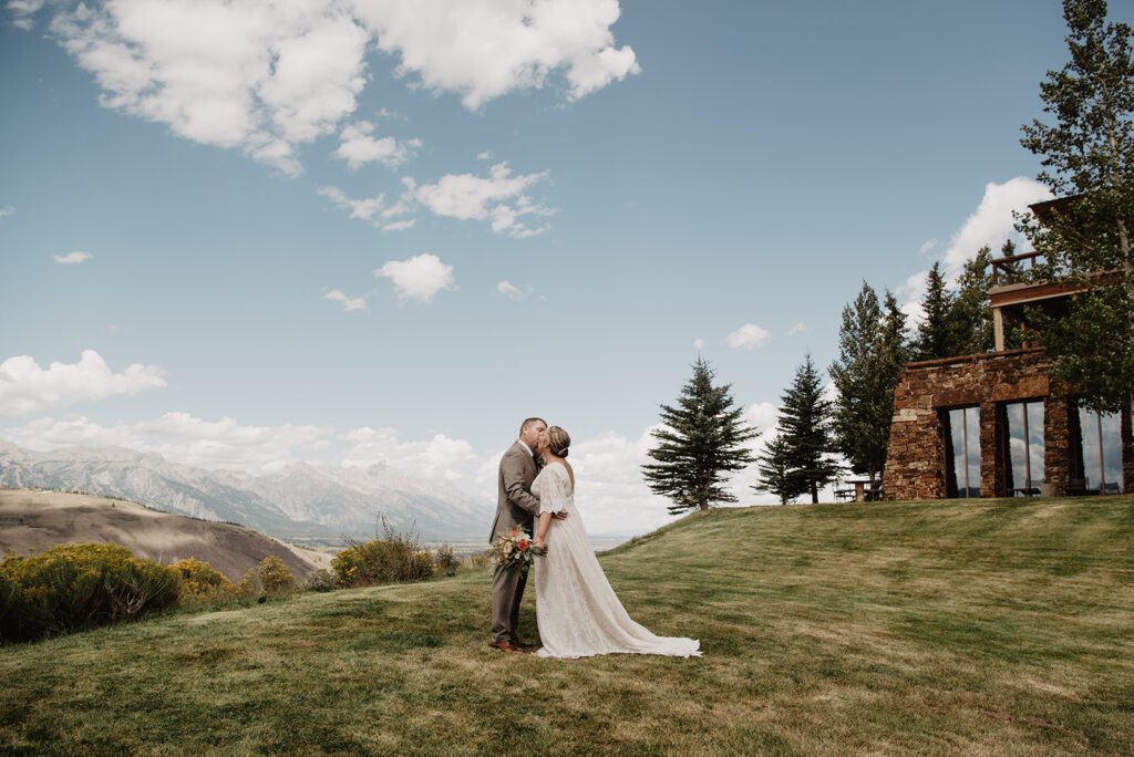 Jackson Hole Elopement Photographer captures bride and groom kissing on grassy hill
