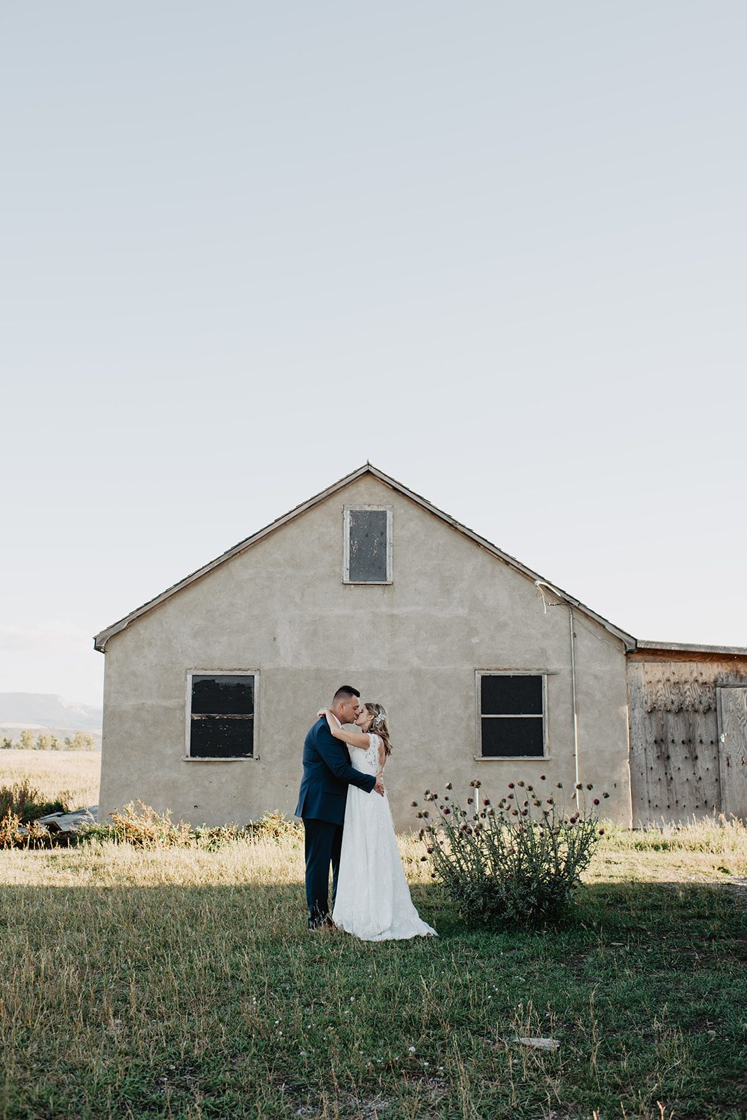 Jackson Hole Photographer captures bride and groom embracing in front of barn