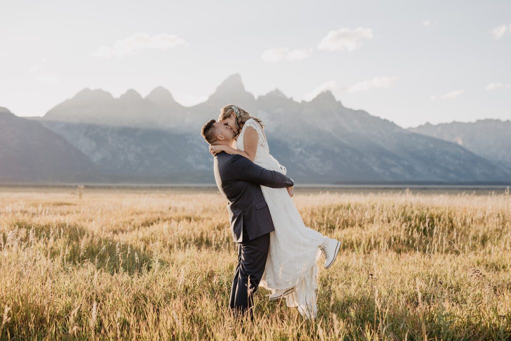 Jackson Hole Photographer captures groom lifting bride and kissing her