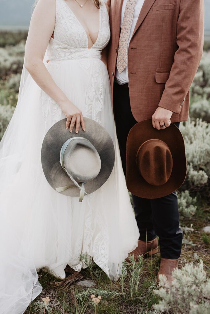 Jackson Hole elopement photographer captures couple holding hats after wyoming elopement