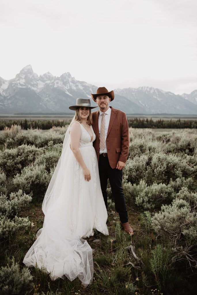 Jackson Hole elopement photographer captures bride and groom wearing wedding attire and cowboy hats after wyoming elopement