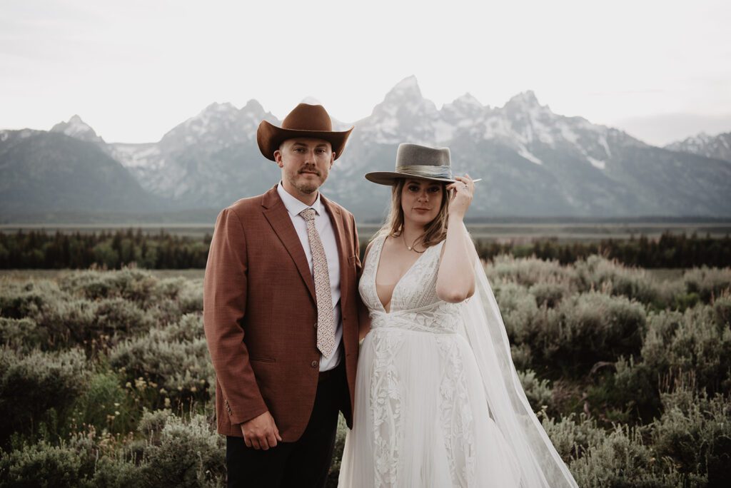 Jackson Hole elopement photographer captures bride and groom wearing hats with wedding attire