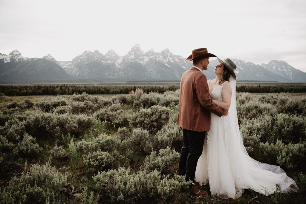 Jackson Hole elopement photographer captures bride and groom wearing hats and hugging