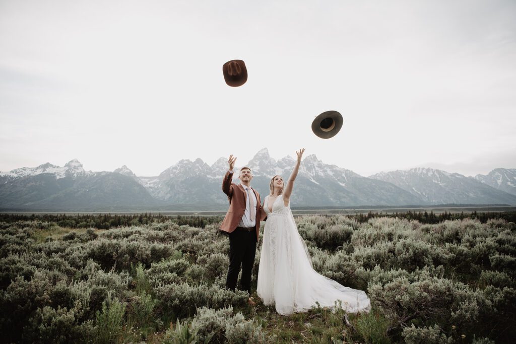 Jackson Hole Elopement Photographer captures bride and groom throwing hats in the air 