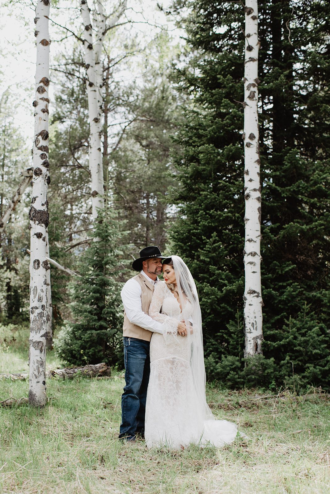 Jackson Hole wedding photographer captures groom standing behind bride and holding her waist while she leans back to kiss him over her shoulder