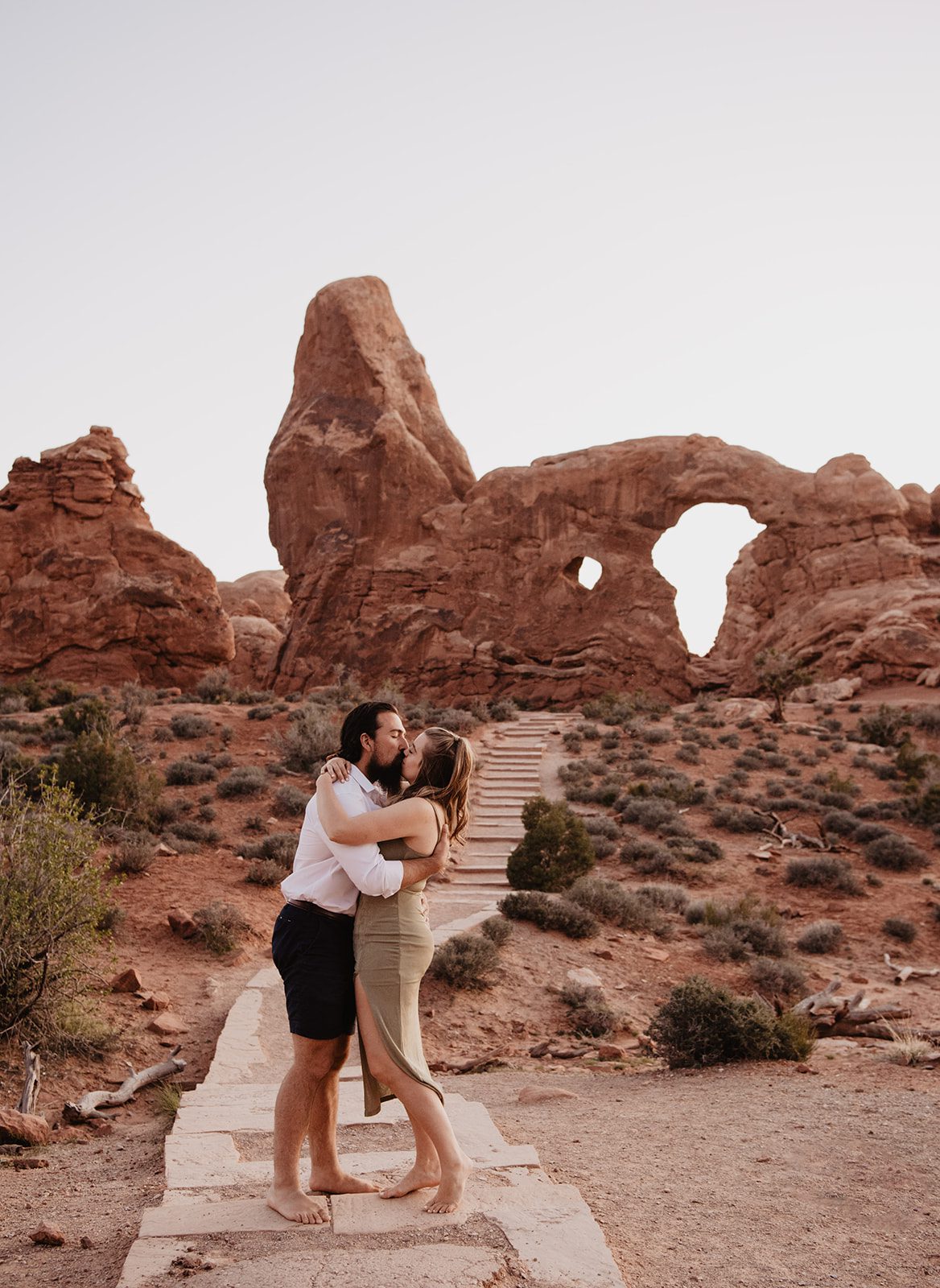 Utah engagement photographer captures Arches National Park wedding location with couple embracing