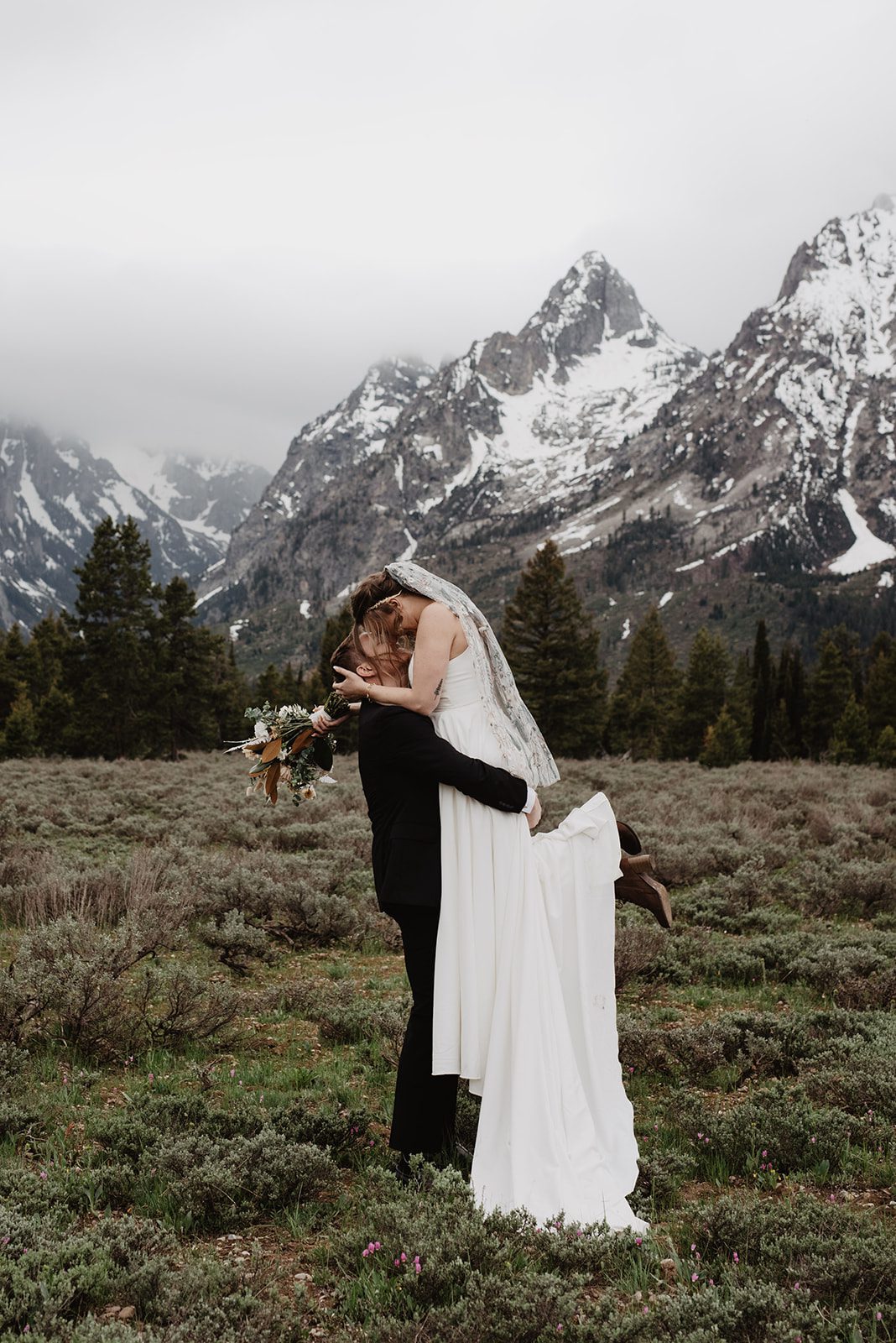 Grand Teton elopement photos with bride and groom kissing in front of the mountains