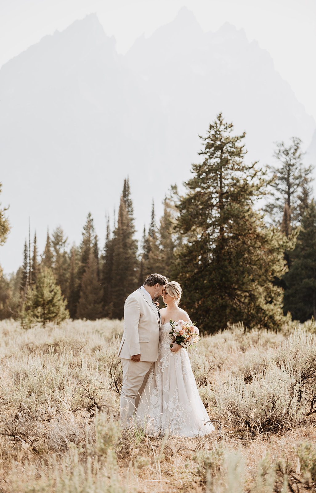 Jackson Hole photographer photographs bride and groom embracing in an opening in the forest in the Tetons